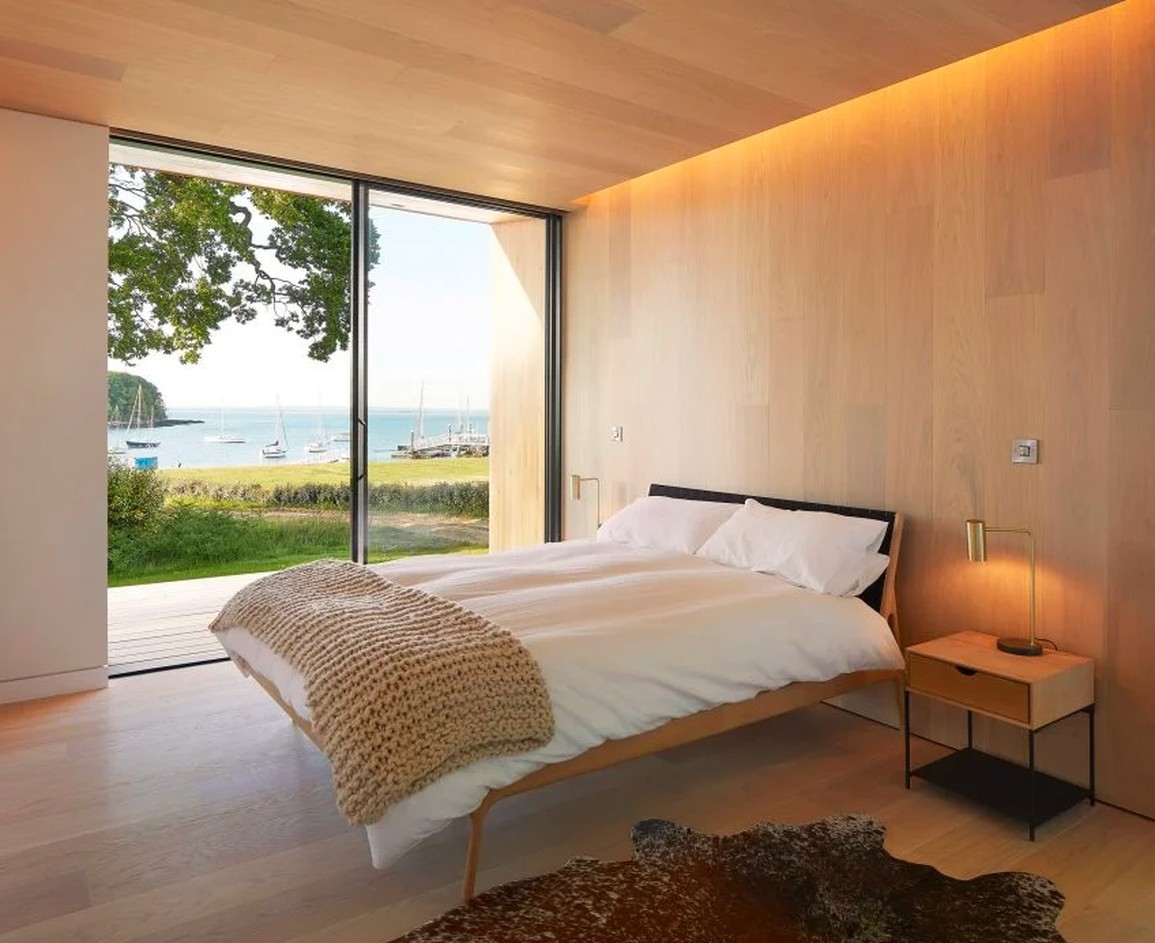 Phòng ngủ tại Island Rest với sàn và tường ốp gỗ thông sáng màu, mang lại cảm giác ấm áp và thanh thoát, một ví dụ về cách để có phòng ngủ ấm cúng