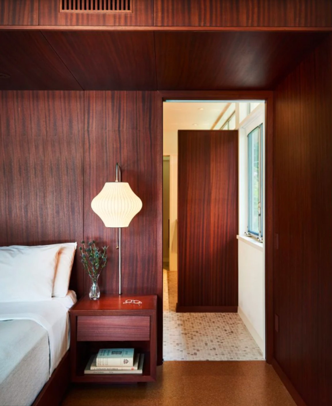 Tường ốp gỗ đào hoa tâm ấm áp kết hợp sàn gỗ sồi tối màu tại nhà Balcones, minh chứng cho sự hiệu quả của gỗ để có phòng ngủ ấm cúng