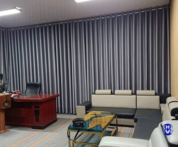 Rèm vải màu xám đậm ngăn cách không gian làm việc và phòng ngủ, tạo sự riêng tư
